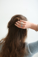 Beautiful young woman with stylish bijouterie doing her hair on white background