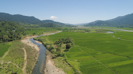 Mountain valley with river, farmland, rice fields. Aerial view of Mountains with green tropical rainforest, trees, jungle with blue sky. Philippines, Luzon.