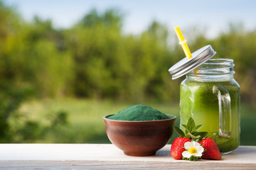 Green smoothie with spirulina on wood background