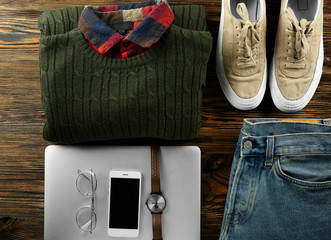 Set of stylish male clothes, accessories and laptop on wooden background