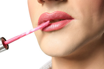 Young transgender man applying makeup on white background, closeup