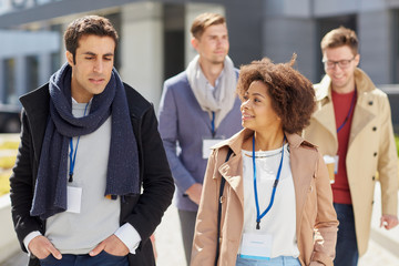 business, education and corporate concept - international group of people with conference badges on city street
