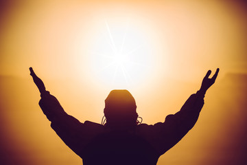 Silhouette of man praying at the top mountain with abstract sun cross ray god power
