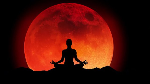 Female silhouette meditating under a super blood wolf moon.