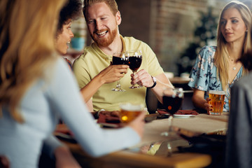 Friends making a toast while sitting in restaurant. Multi-ethnic group.