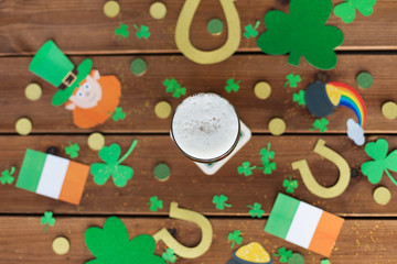st patricks day, holidays and celebration concept - glass of draft beer and party props on wooden table top view