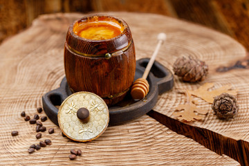 Open barrel with honey on a wooden saw and cedar cones.