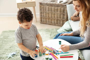Cute little boy with mother drawing at home