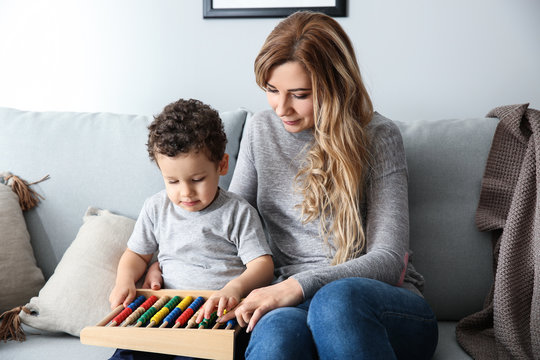 Young mother with cute little son playing with abacus at home - Powered by Adobe