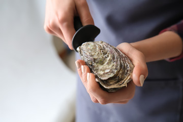 Woman opening raw oyster with knife, closeup