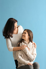Portrait of young woman with her mother on color background