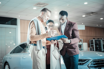 Man wearing beige trousers signing documents for insurance of car