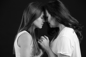 Black and white portrait of young woman with her mother on dark background