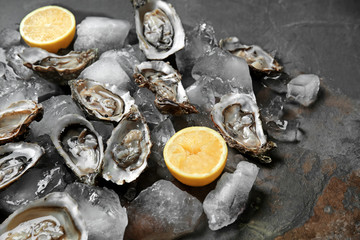 Tasty raw oysters with ice and lemon on dark background