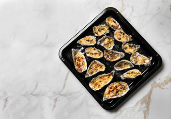 Baking sheet with tasty cooked oysters on light table