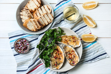 Plates with tasty baked oysters and grilled bread on table
