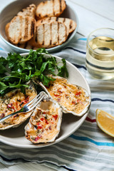Plate with tasty baked oysters on table