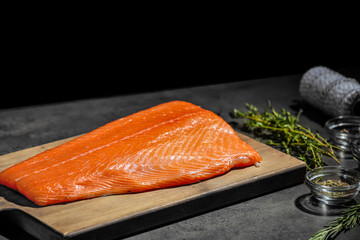 Board with fillet of fresh salmon on table