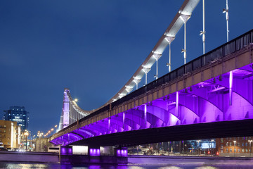 Krymsky Bridge or Crimean bridge in Moscow, Russia night view with purple illumination, suspension steel bridge over the Moscow River evening time cityscape with lanterns lights on the city streets