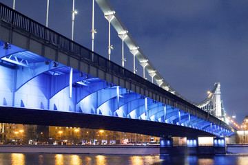 Krymsky Bridge or Crimean bridge in Moscow, Russia night view with blue illumination, suspension steel bridge over the Moscow River evening time cityscape with lanterns lights on the city streets