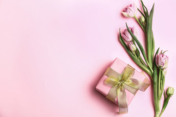 Fototapeta na wymiar Festive gift box and flowers on color background