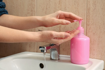 Woman washing hands with liquid soap in bathroom