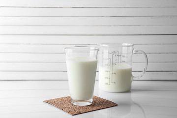 Glass and jug of fresh milk on table