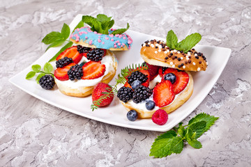Morning breakfast with mini donuts and berries on plate under powdered sugar on grey background. Tasty donuts closeup. Donuts cut with filling