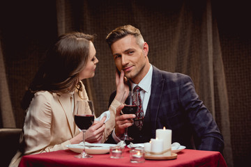 woman touching face of handsome man during romantic date in restaurant