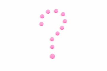 Symbol question mark made from pink pills or tablets on white background.