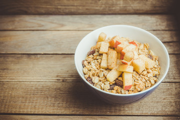 Healthy and tasty breakfast with muesli, apples, nuts and cinnamon. Selective focus.