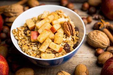 Healthy and tasty breakfast with muesli, apples, nuts and cinnamon. Selective focus.