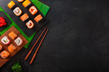 Sushi set with wasabi and ginger on black stone tray on black table. Top view
