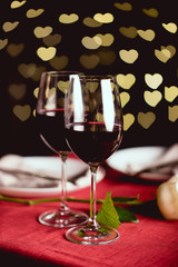 selective focus of red wine glasses with heart shaped bokeh on background