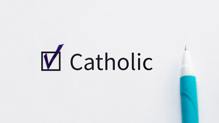 Catholic - checkbox with a tick on white paper with blue pen. Checklist concept.