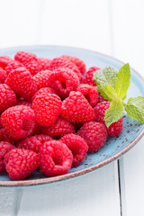 Fresh raspberries in a plate on a  vintage background.