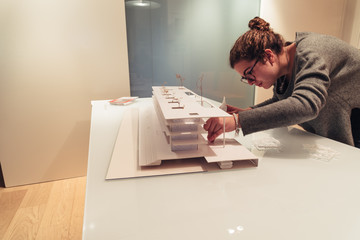 Female architect working on architecture model on table - obrazy, fototapety, plakaty