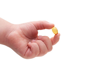 Child's hand holding a capsule of Omega 3 on white background. Close up. High resolution product. Health care concept.