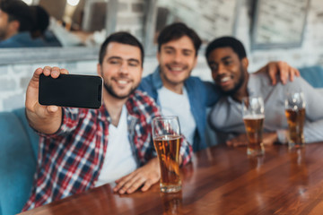 Men taking selfie and drinking beer in bar