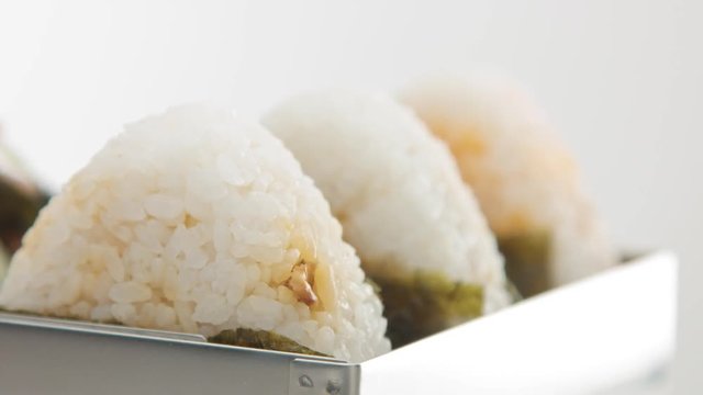 three onigiri in metal bento, changing focus zone from the far one to the close one
