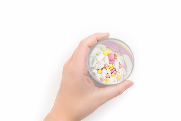 Female hand and glass full of colorful medicines,pills, vitamins or supplements. The concept of addiction treatment