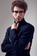 Fototapeta premium Handsome elegant man with curly hair wearing suit and glasses