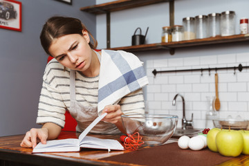 Serious young woman standing at the kitchen at home