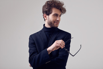 Handsome elegant man with curly hair wearing suit and glasses