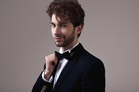 Handsome elegant man with curly hair wearing tuxedo