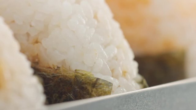macro panned video of three onigiri rice ball texture. Japanece food in bento