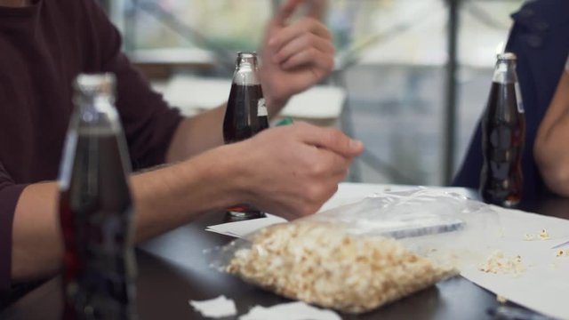 Male team member opens pepsi glass bottle with the help of cigarette lighter for his colleague on the break after hardworking