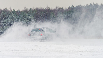 Extreme driving, the car is moving rapidly over the smooth snow and creates a spray of snow.