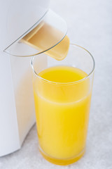 Juicer with a glass of fresh orange juice in a modern kitchen.
