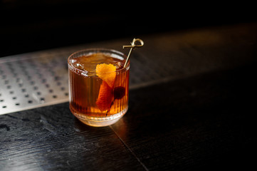 Glass of a Old Fashioned cocktail on the wooden steel bar counter